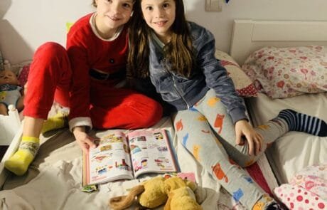 Isabel und ihre Freundin Martina, die Illustratorin des Buches, blättern gemeinsam auf dem Bett sitzend in einem Katalog.