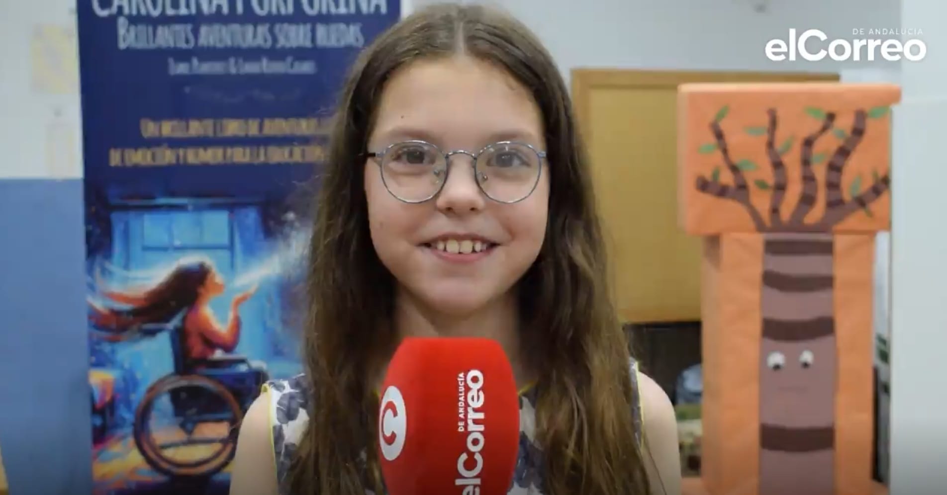 Isabel antwortet mit ihrer runden Brille vor dem Mikrofon von elCorreo de Andalucía, neben dem Roll-up des Buches.