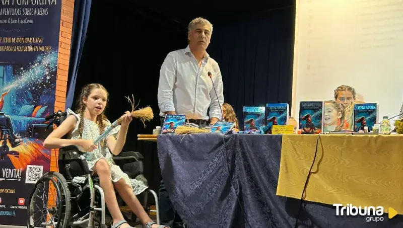 Buchvorstellung in einer Aula: ein Mädchen im Rollstuhl mit einem Strohbesen, neben dem Tisch mit Exemplaren.