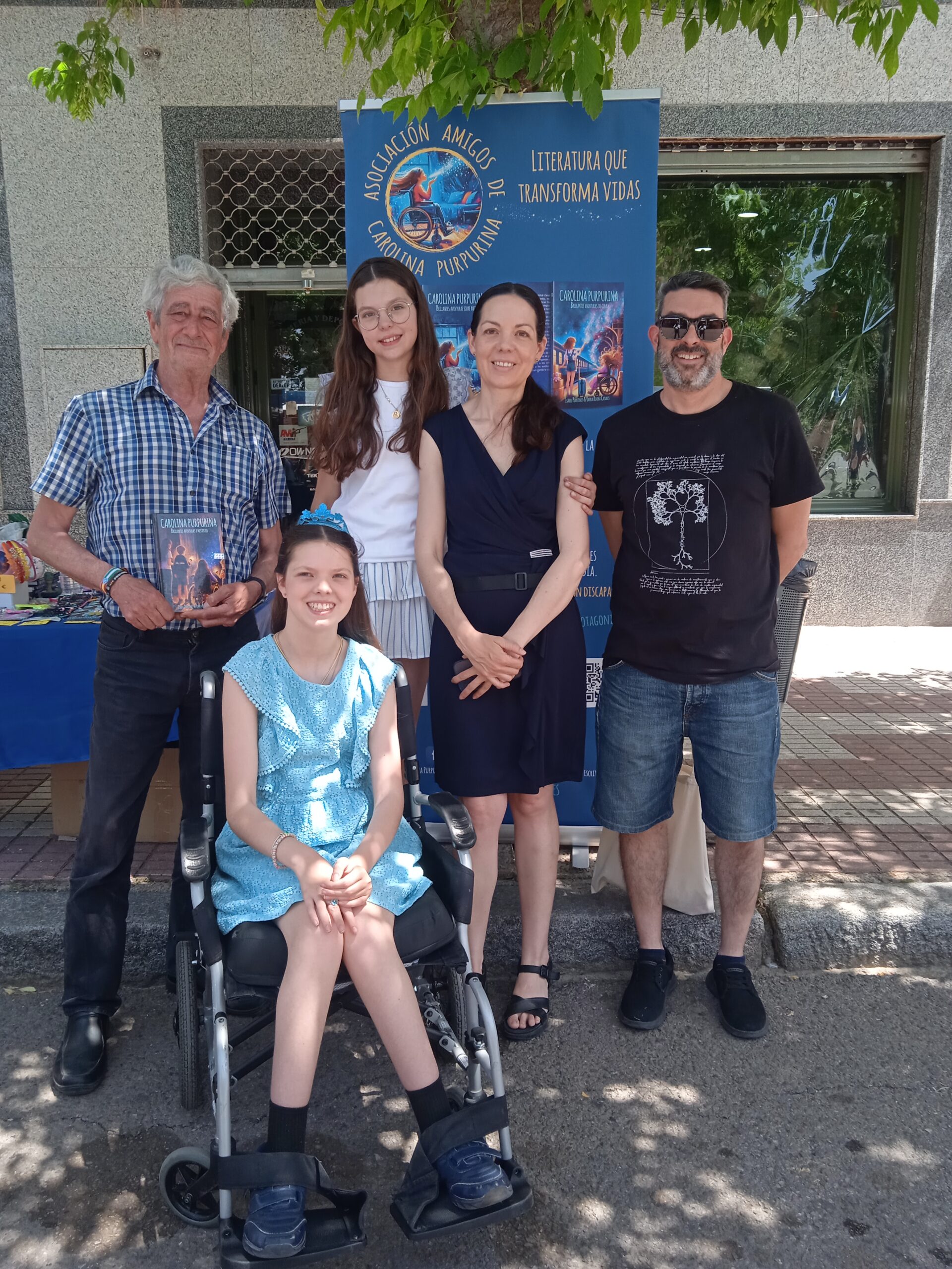 Buchvorstellung: Die Familie posiert vor dem Roll-up der Asociación Amigos de Carolina Purpurina.