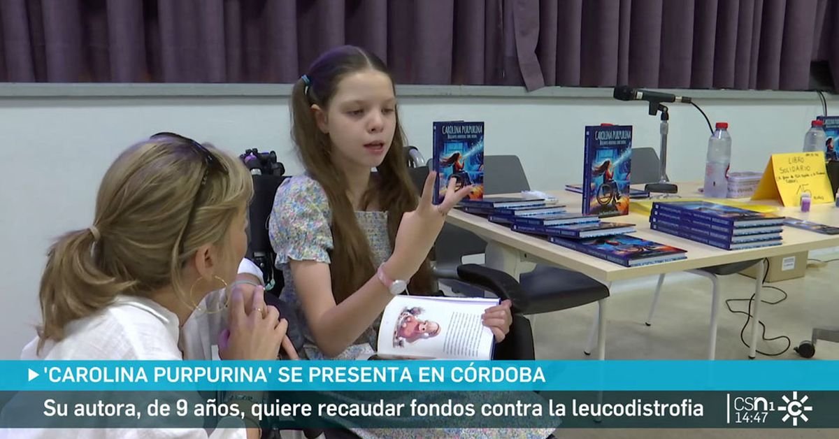 Bericht von Canal Sur in Córdoba: Ein sitzendes Mädchen mit aufgeschlagenem Buch spricht mit einer Frau; dahinter der Tisch mit Exemplaren.